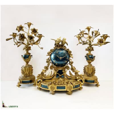 Pendule en bronze doré et métal bleu métallisé à décor de fleurs et couple de tourterelles, haut. 32 cm, avec deux candélabres à trois bras de lumière, haut. 40 cm, (Fin XIXe)
