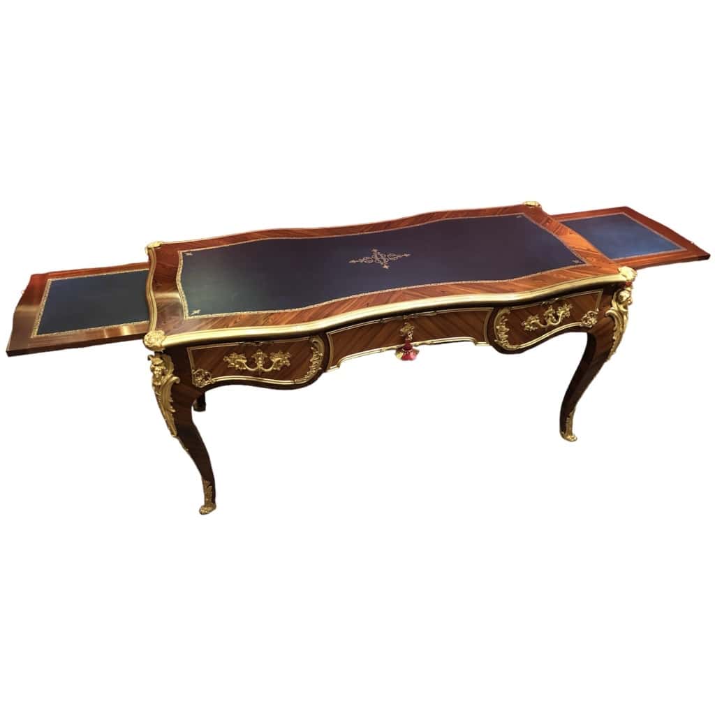 Louis XV style flat desk in rosewood and violet wood veneer, opening with three belt drawers and resting on arched legs. 21