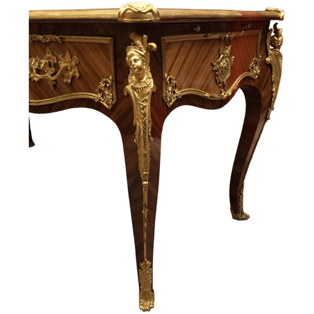 Louis XV style flat desk in rosewood and violet wood veneer, opening with three belt drawers and resting on arched legs. 15