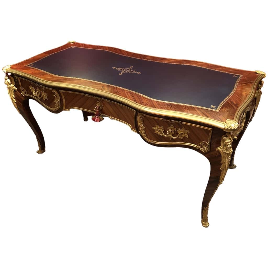 Louis XV style flat desk in rosewood and violet wood veneer, opening with three belt drawers and resting on arched legs. 13