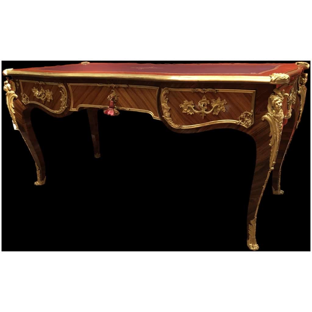 Louis XV style flat desk in rosewood and violet wood veneer, opening with three belt drawers and resting on arched legs. 14