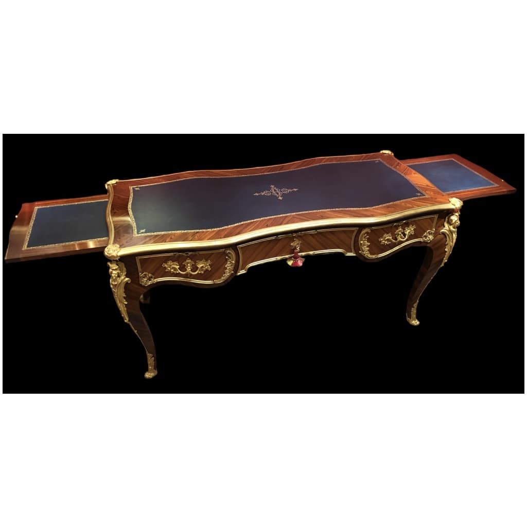 Louis XV style flat desk in rosewood and violet wood veneer, opening with three belt drawers and resting on arched legs. 22