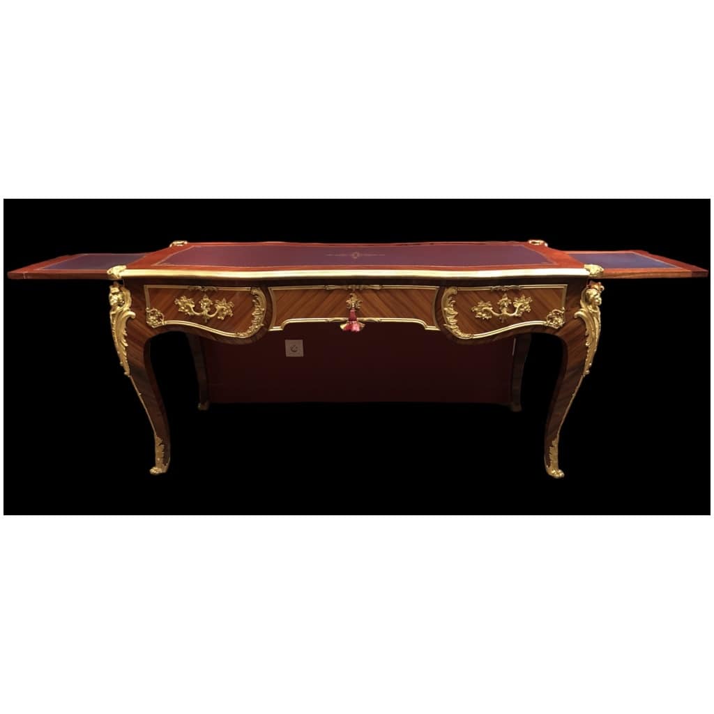 Louis XV style flat desk in rosewood and violet wood veneer, opening with three belt drawers and resting on arched legs. 23