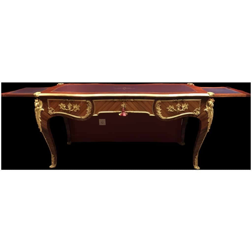 Louis XV style flat desk in rosewood and violet wood veneer, opening with three belt drawers and resting on arched legs. 24