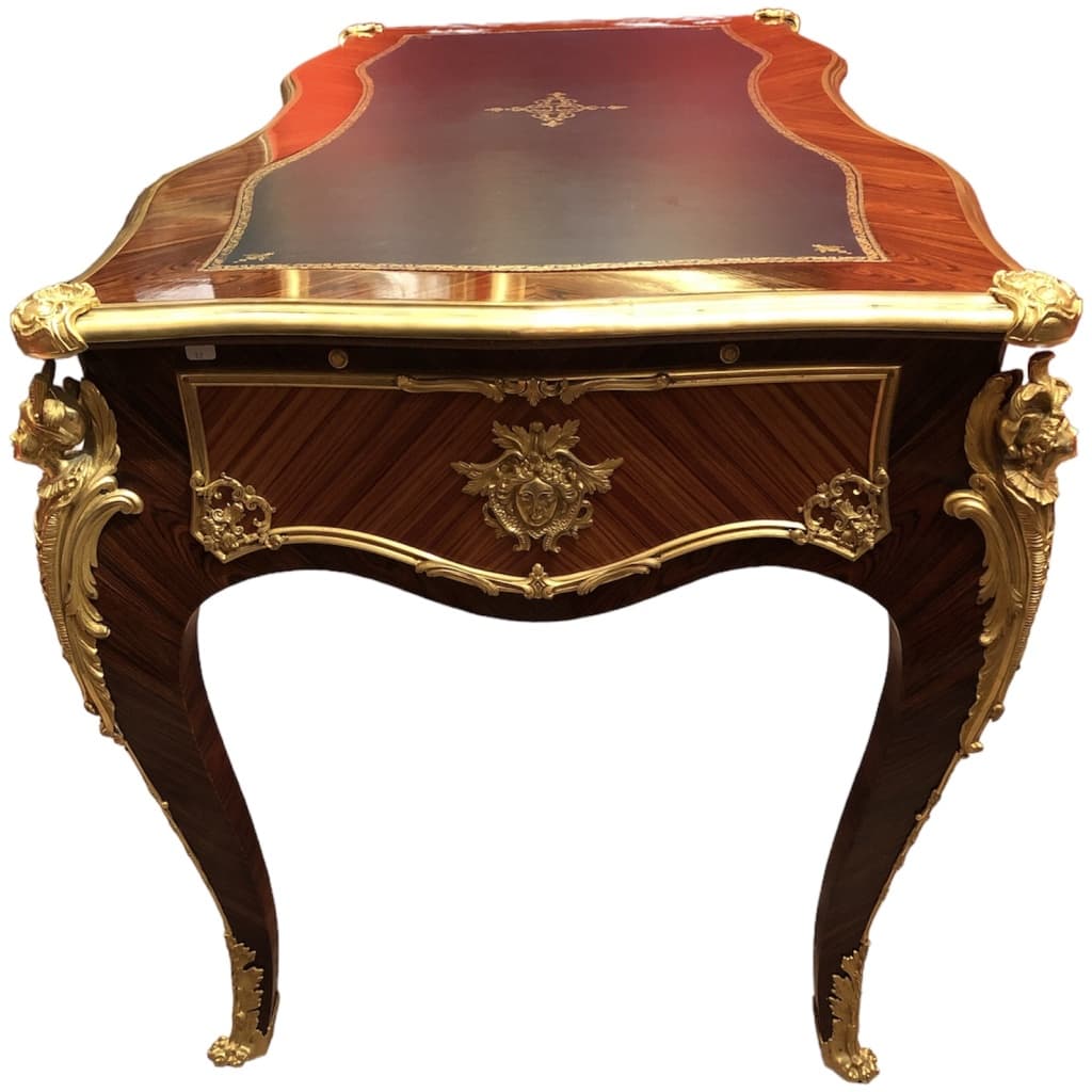 Louis XV style flat desk in rosewood and violet wood veneer, opening with three belt drawers and resting on arched legs. 20