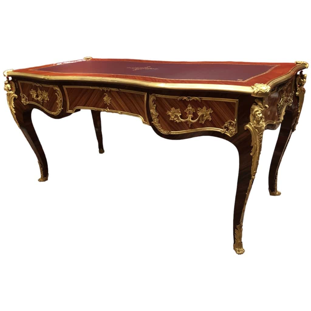 Louis XV style flat desk in rosewood and violet wood veneer, opening with three belt drawers and resting on arched legs. 19