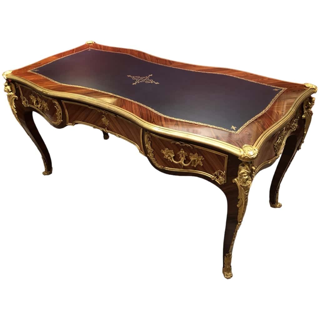 Louis XV style flat desk in rosewood and violet wood veneer, opening with three belt drawers and resting on arched legs. 18