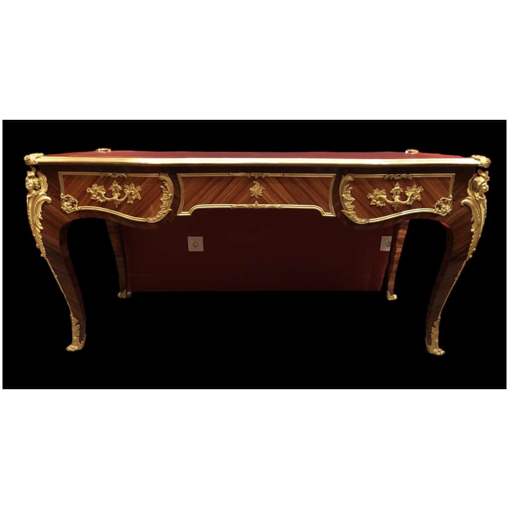 Louis XV style flat desk in rosewood and violet wood veneer, opening with three belt drawers and resting on arched legs. 16