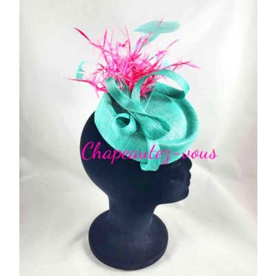 Chapeau – Bibi en sisal forme Jackie, fait à la main. Cette création est agrémentée d’un ruban de biais et de plumes biot fushia ainsi que de plumes de coq turquoise clair – Fascinator