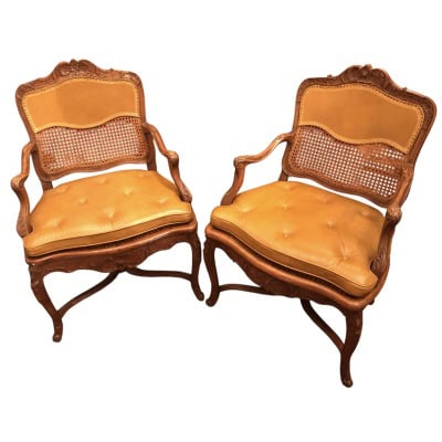 Paire de fauteuils à dossier plat d’époque Régence à fond de canne en bois naturel sculpté.